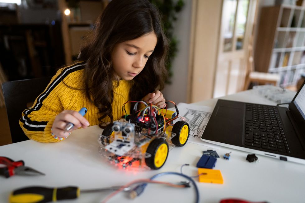 dedicated schoolgirl, observing the prototype of robotic car, she testing
